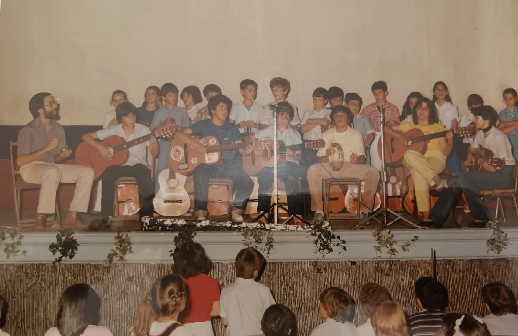 Una actuación con guitarras en el escenario, con los alumnos de público
