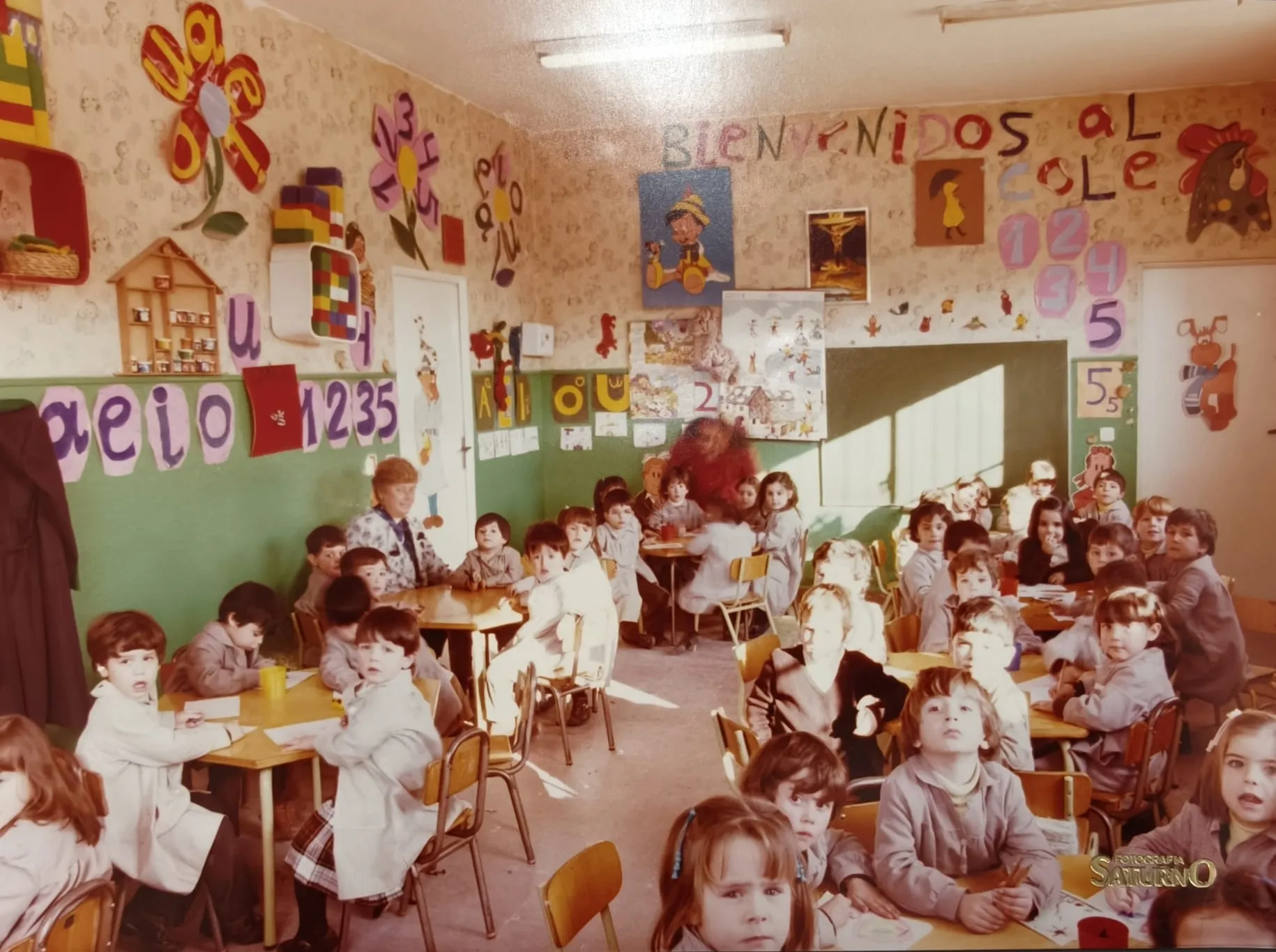 Un aula de Infantil con el cartel «Bienvenidos al cole» y los niños en sus mesas