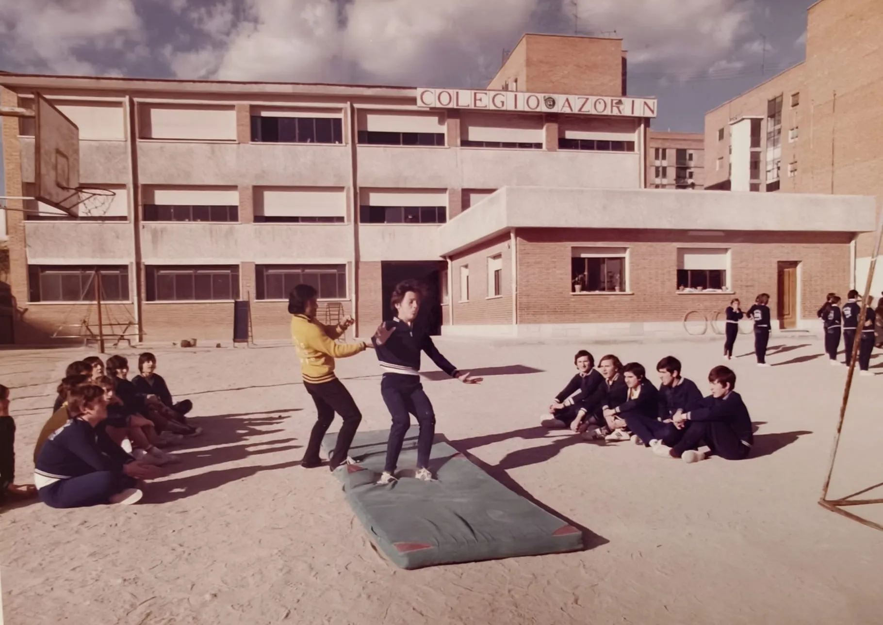 El edificio del colegio con el rótulo «Colegio Azorín» y una clase de gimnasia en el patio